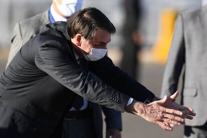 Jair Bolsonaro saluda con mascarilla a una niña (fuera de plano) en Brasilia el pasado 12 de mayo.