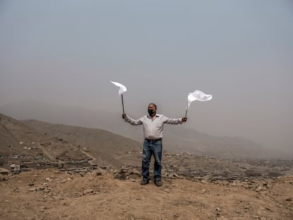 Un habitante del distrito de Carabayllo, Lima (Perú), sacude las banderas blancas para solicitar alimentos. 