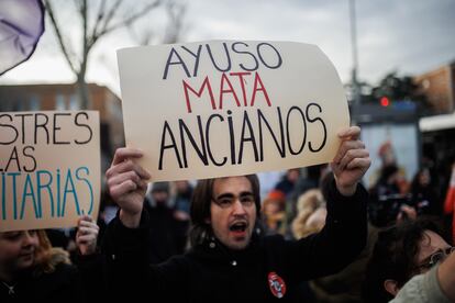 Un hombre con un cartel en el que se lee: 'Ayuso mata ancianos' durante la concentración en contra de la distinción de la presidenta de la Comunidad de Madrid como Alumna Ilustre de la Complutense, en las inmediaciones de la Universidad Complutense, a 24 de enero de 2023.