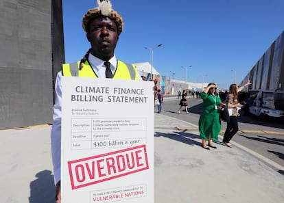Un manifestante sostiene una pancarta contra la malversación de recursos económicos frente la crisis climática, durante la COP27, el día 9.