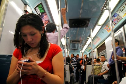 Una joven utiliza su teléfono inteligente mientras viaja en el metro de Ciudad de México.