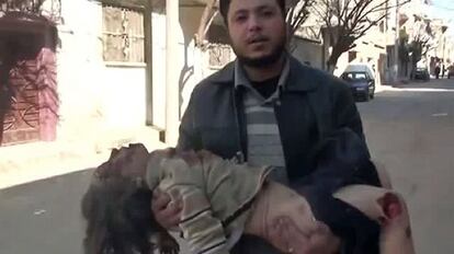 Captura de un vídeo que muestra a un hombre sujeta el cuerpo de una niña muerta en Homs.