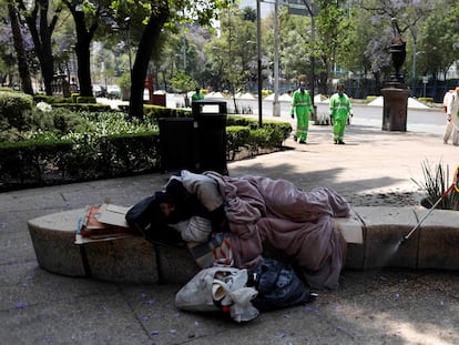 Agentes sanitários lavam praça no México, enquanto morador de rua dorme, em uma imagem de abril do ano passado.