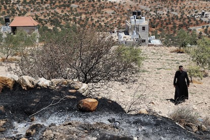 Un sacerdote, este lunes, junto a parte del terreno quemado por colonos judíos junto a la iglesia de San Jorge de Taybeh (Cisjordania).