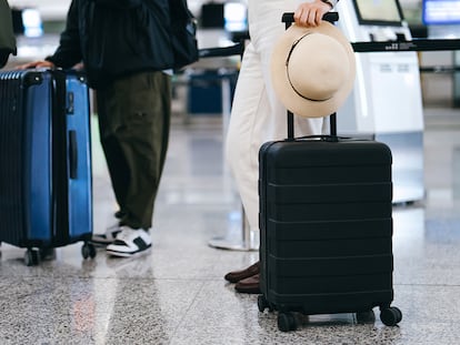 Unas personas haciendo cola en el aeropuerto con sus maletas.