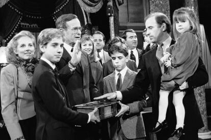 Joe Biden (à direita), com sua filha Ashley em braços, durante o ensaio de juramento em frente ao vice-presidente George Bush, no Capitólio de Washington, quando era membro do Senado, em 1985.