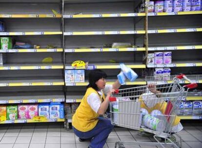 Una dependienta de un supermercado en Hefei retira las fórmulas contaminadas de leche en polvo