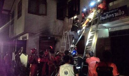 Los bomberos rescatan a una de las estudiantes del fuego en una residencia femenina de Tailandia.