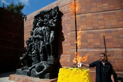 Un hombre prende una antorcha junto a una escultura conmemorativa, antes de la ceremonia, el 24 de abril de 2017, en Jerusalén (Israel).