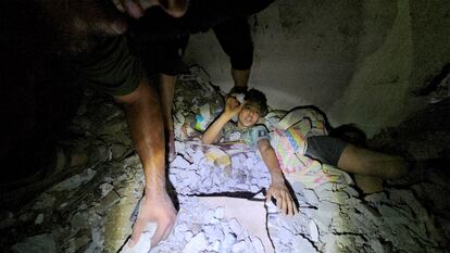 Voluntarios trabajan para liberar a un niño atrapado entre los escombros tras un bombardeo israelí en Jabalia, al norte de Gaza. 