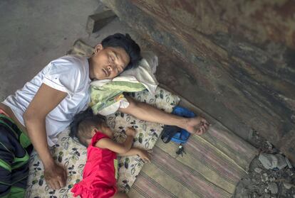 Un padre está descansando con su hija en la sombra de un barco varado en el puerto de Tacloban. Mayo es uno de los meses más calurosos del año en Filipinas.