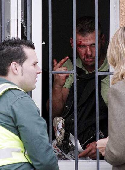 El secuestrador, con sangre en la frente, habla tras una ventana del bar con un guardia civil y una intérprete.