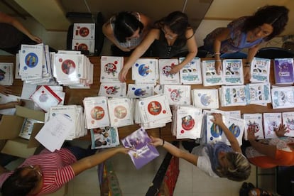 Padres y madres de un colegio público preparan los libros que han comprado por cooperativa.