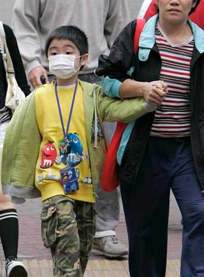 Un niño pasea con mascarilla en la ciudad de Hong Kong tras el cierre de las aulas ante la nueva epidemia de gripe