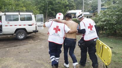 Dos miembros del personal técnico en emergencias médicas de Cruz Roja Nicaragüense ayudan a un paciente a caminar hasta la ambulancia.