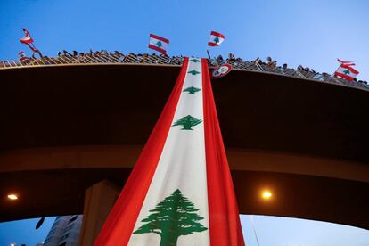 Manifestantes en un puente del que cuelga una bandera nacional durante una protesta antigubernamental a lo largo de una carretera en Jal el-Dib (Líbano).
