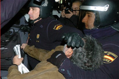 Dos policías retienen a uno de los participantes de la "sentada" en Gran Vía.