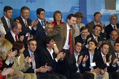 Mariano Rajoy, rodeado de ministros y parlamentarios, poco antes de su intervención ante los candidatos del PP al Congreso y al Senado.