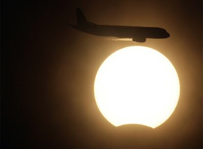 Un avión surca el cielo durante el eclipse en Nueva Delhi.