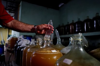 Orestes Estevez revisa un condón usado en la producción de vino en su bodega improvisada, en La Habana (Cuba).