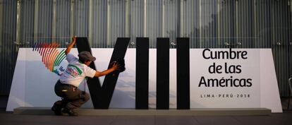 Una mujer limpia el logo de la Cumbre de las Américas en Lima.