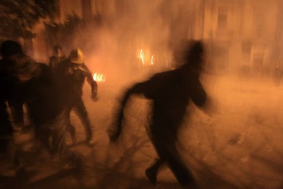 Manifestantes corren en medio del humo durante los enfrentamientos con la policía cerca del ministerio del Interior.