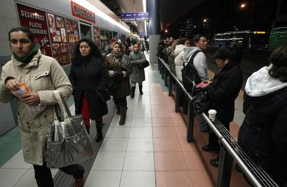 Usuarios de la EMT esperan la llegada de los autobuses en el intercambiador de Plaza Castilla, Madrid.