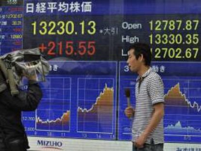 Un equipo de televisión informa junto a una pantalla que muestra información financiera en Tokio (Japón). EFE/Archivo