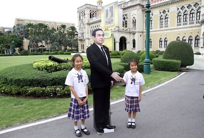 Niños en la sede del gobierno tailandés posando junto al recortable del primer ministro.