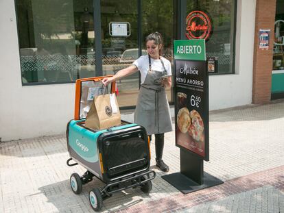 Una empleada de un restaurante deposita un pedido en un robot de reparto, en Alcobendas.