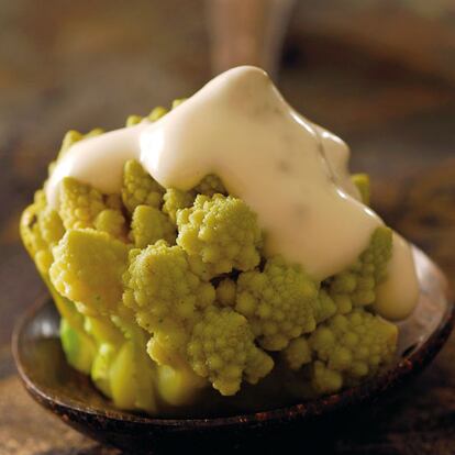 PARA CUATRO PERSONAS: 1 kilo de romanesco, 1 cucharada de aceite, 1 cucharada de queso rallado. PARA LA SALSA DE QUESO: 1 tarrina de queso fresco tipo Speissequark 0% de materia grasa, sal, pimienta blanca molida, 1 punta de cuchillo de cayena, 1 cucharada de cebollino picado. UNO: Separar el romanesco en ramos (o elegir romanescos 'mini'), lavarlo, escurrirlo y cocerlo en agua hirviendo con sal y con el aceite durante 12-15 minutos. Escurrirlo y pasarlo unos segundos por un cuenco lleno de agua helada para fijar el color. Escurrirlo de nuevo y reservarlo. DOS: Engrasar con aceite una fuente de horno y poner las ramitas de romanesco bien colocadas. Verter por encima la salsa de queso, espolvorearlo con el queso rallado y gratinarlo en el horno durante unos 15 minutos. SALSA DE QUESO: Mezclar el queso con la sal, la pimienta blanca, la cayena y el cebollino picado. Si se quiere una salsa más ligera, añadir 2 cucharadas de leche. PRESENTACIÓN: Servir recién sacado del horno.
