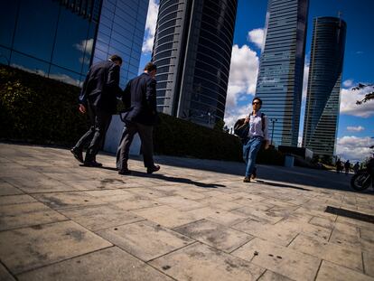 Varias personas pasean por la zona financiera de las cuatro torres en Madrid.