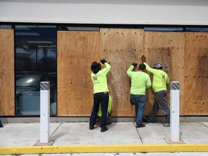 Trabalhadores de Miami cobrem as fachadas dos edifícios ante a possível chegada do furacão Dorian.