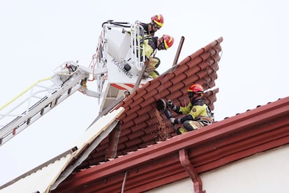 Varios bomberos trabajan en la retirada de parte de un tejado que el fuerte viento ha arrancado frente a la estación del Norte de Valladolid, este miércoles. 