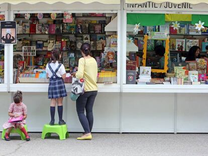 Dos ni&ntilde;as hojean libros en la Feria del Libro de Madrid.