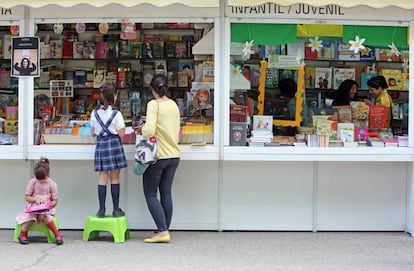Dos ni&ntilde;as hojean libros en la Feria del Libro de Madrid.
