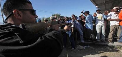 Un agente de la policía jordana que forma parte de las fuerzas de seguridad de la ONU dispara gases lacrimógenos contra una multitud de haitianos.