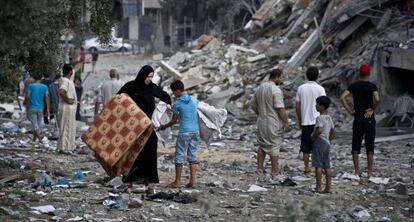 Una mujer lleva sus pertenencias con la ayuda de un ni&ntilde;o en Gaza. 