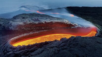 Río de fuego del volcán Etna, en Italia. Como "hipnótico" describe el fotógrafo Luciano Gaudenzio la lengua de fuego que se deslizaba lentamente ante él: "una herida abierta en la piel arrugada y áspera de un dinosaurio". La imagen se tomó en 2017, cuando se encontraba en la cercana isla de Stromboli para fotografiar erupciones cuando llegó a sus oídos que el mayor volcán de Europa se ponía en acción. La imagen se tomó justo después del ocaso, en la llamada "hora azul", lo que obra un enorme contraste de colores en la imagen. La imagen ha recibido el primer premio de la categoría "Entornos de la Tierra".