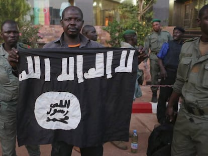 Agentes maliense muestran una bandera yihadista hallada en un hotel de Bamako, atacado en noviembre de 2015.