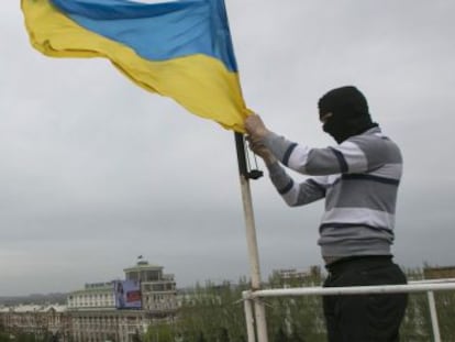 Un activista prorruso arr&iacute;a una bandera ucrania en un edificio oficial en Donetsk.