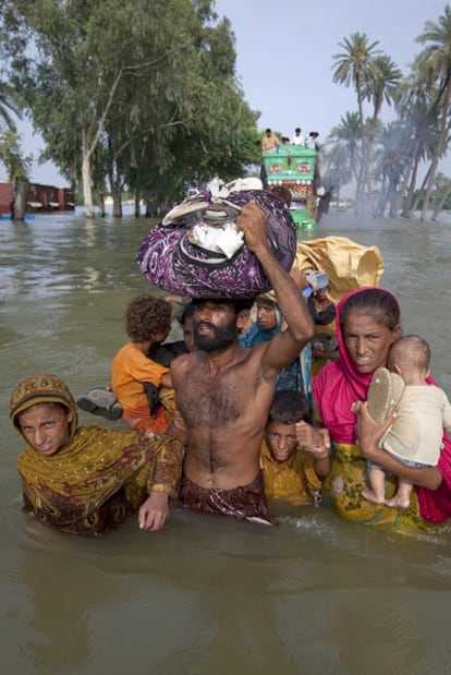 Una familia paquistani camina con el agua por la cintura por el distrito totalmente inundado de Punjab, provincia de Muzaffargarh.