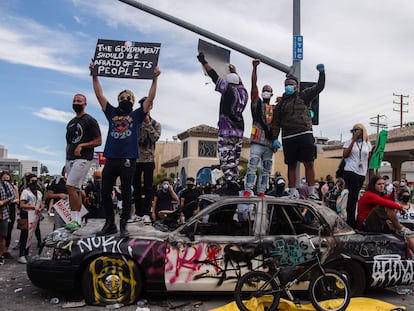 Manifestantes saltan sobre un vehículo policial dañado en Los Ángeles este domingo.
