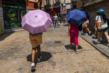 Dos personas pasean protegiéndose del calor con paraguas en una calle de Toledo, donde sigue este martes en alerta naranja por altas temperaturas.