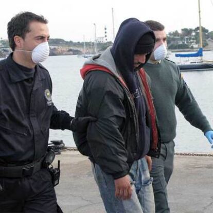 Agentes de la Guardia Civil y de la policía escoltan a uno de los inmigrantes llegados a Mallorca.