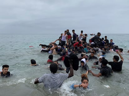 Un grupo de personas se hacen con una embarcación de las autoridades marroquíes en la playa de la localidad de Fnideq (Castillejos) para cruzar los espigones de Ceuta, el 18 de mayo de 2021.