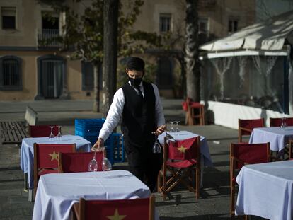 Un camarero prepara las mesas de una terraza en Barcelona.