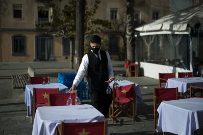 Un camarero prepara mesas en un restaurante de Barcelona.