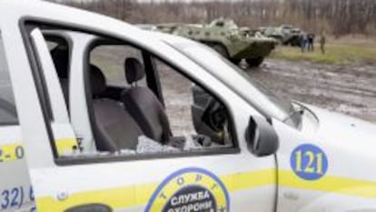 Un veh&iacute;culo da&ntilde;ado en Slaviansk, tras los choques armados entre activistas prorrusos y soldados ucranianos (al fondo).