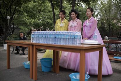 Mujeres con vestidos tradicionales ofrecen agua durante la visita de los periodistas.